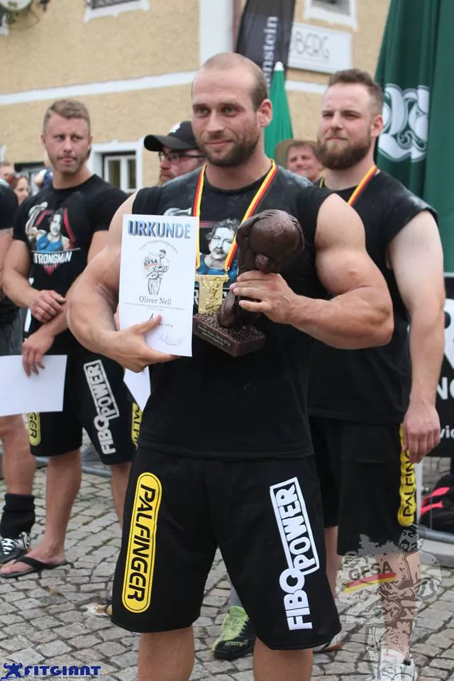 Oliver Nell mit Urkunde und Pokal bei einem Strongman-Wettkampf